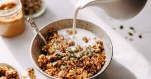 Protein granola clusters with golden brown oats and seeds in white ceramic bowl