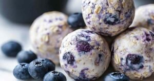 Blueberry Cheesecake Protein Bites arranged on white plate showing creamy texture and fresh blueberries