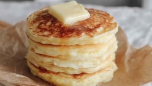 Stack of fluffy cottage cheese hot cakes drizzled with maple syrup showing perfect golden color
