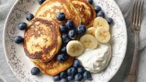 Stack of golden protein pancakes on white plate with syrup drizzle showing fluffy texture