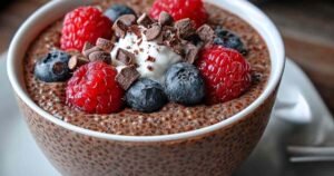 High protein chocolate chia seed pudding served in mason jars with fresh berries on top