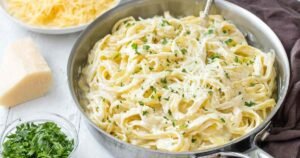 Cottage cheese Alfredo pasta garnished with parmesan and parsley in white bowl