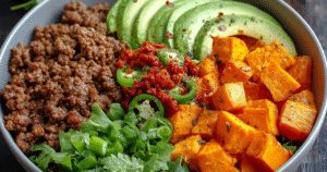 Spicy ground beef sweet potato protein bowl topped with cottage cheese and avocado in white bowl