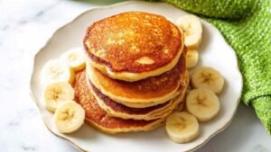 Stack of golden cottage cheese pancakes on white plate showing fluffy texture and height