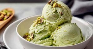 High-protein pistachio ice cream served in white bowl topped with chopped pistachios and honey drizzle