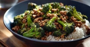 Honey sriracha ground chicken and broccoli cooking in skillet with glossy sauce coating