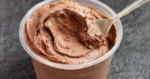 Keto ninja creami ice cream with chocolate peanut butter in clear container showing creamy texture