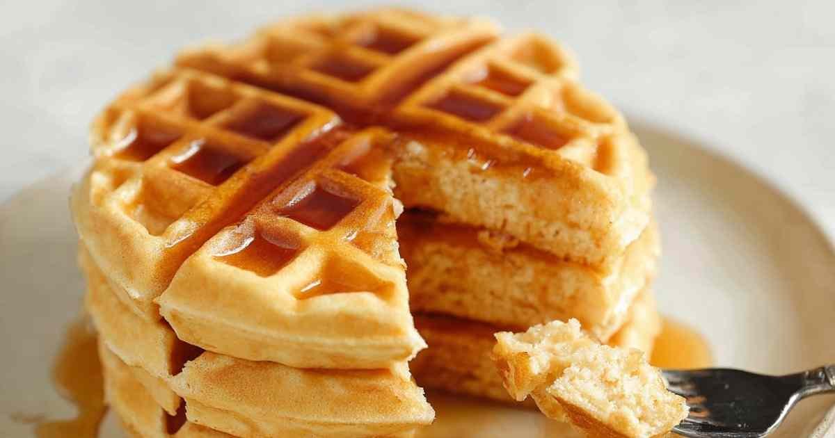 Protein powder waffles served on white plate with butter and sugar-free syrup drizzled on top
