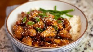 Healthy sesame chicken served over rice with green beans and sesame seeds