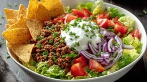 Cottage cheese nacho bowl with seasoned ground beef, tortilla chips, and fresh toppings in a white bowl