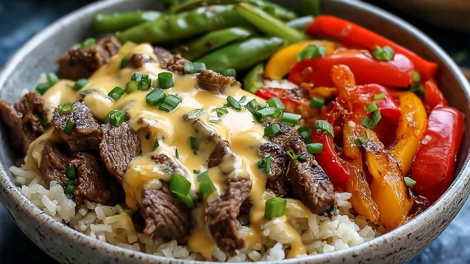 High protein Philly cheesesteak rice bowl with steak, cheese sauce, and vegetables