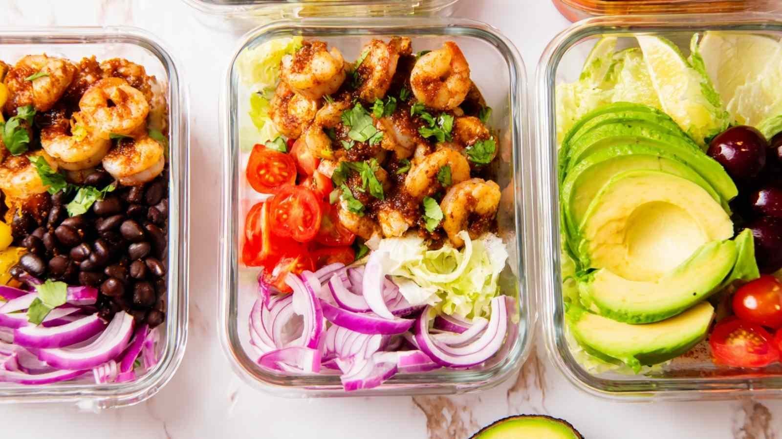 High protein shrimp taco rice bowl with seasoned shrimp, black beans, avocado, and fresh vegetables