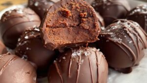 Brownie protein bites stacked on white plate showing fudgy texture