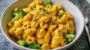 High protein vegan mac and cheese with broccoli and chickpea pasta in white bowl showing creamy cheese sauce