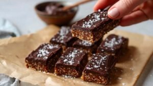 Homemade protein bars ingredients including dates peanut butter oat flour protein powder arranged on marble counter